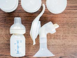 Background of manual breast pump and baby bottle with milk